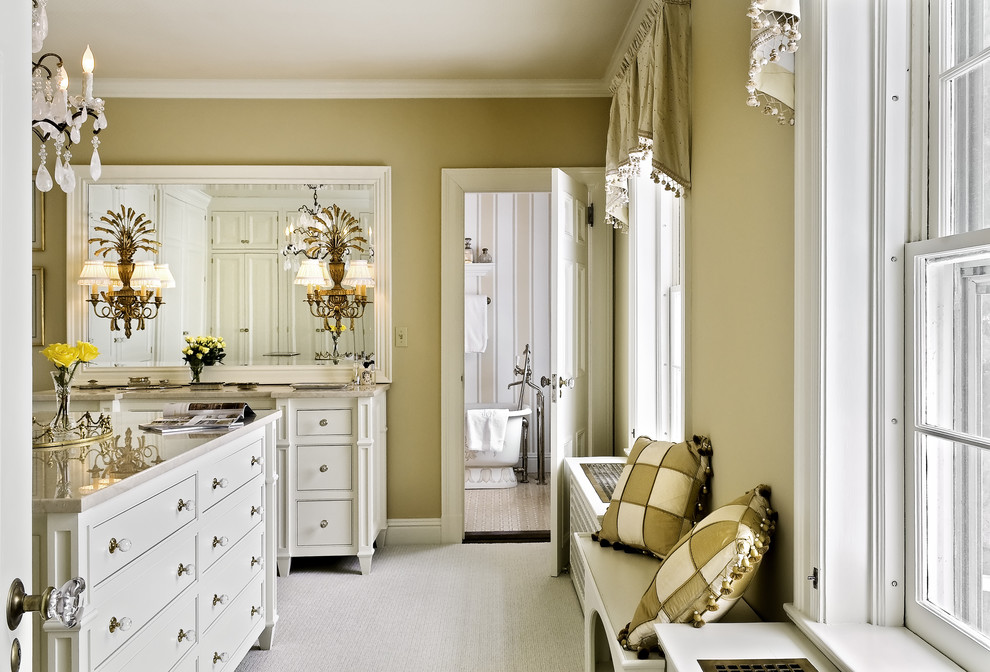 This is an example of a traditional dressing room in New York with carpet and white cabinets.