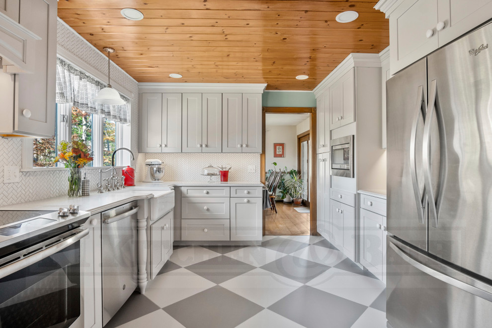 Bild på ett stort vintage vit vitt kök, med en rustik diskho, skåp i shakerstil, grå skåp, bänkskiva i kvarts, vitt stänkskydd, stänkskydd i keramik, rostfria vitvaror, en köksö och flerfärgat golv