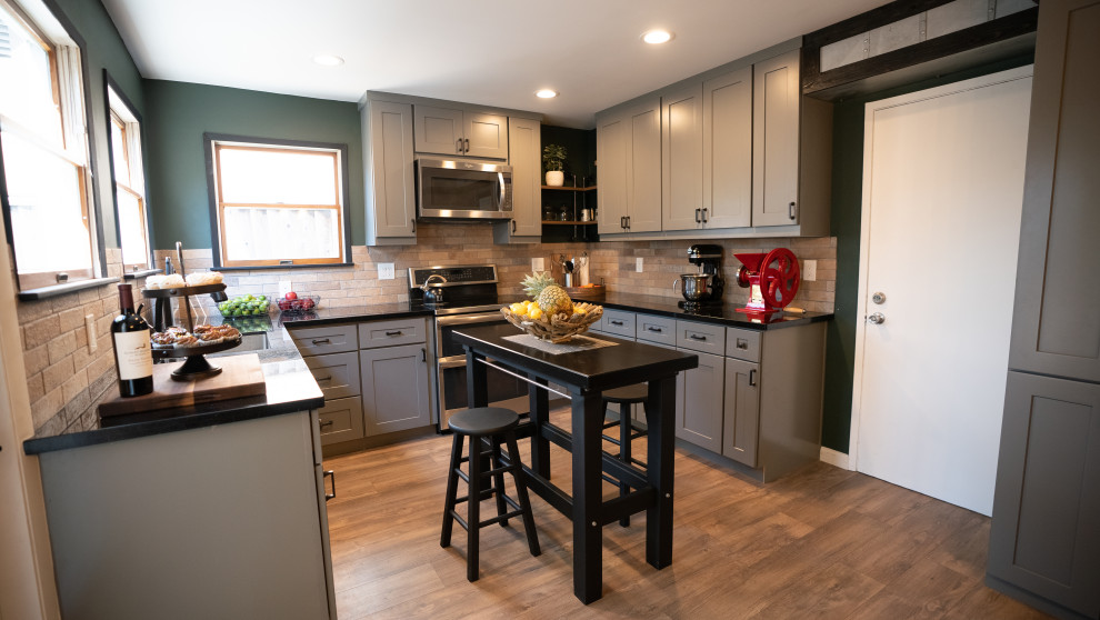 Mid-sized industrial u-shaped eat-in kitchen in San Francisco with an undermount sink, shaker cabinets, grey cabinets, quartz benchtops, red splashback, brick splashback, stainless steel appliances, vinyl floors, with island, brown floor and black benchtop.