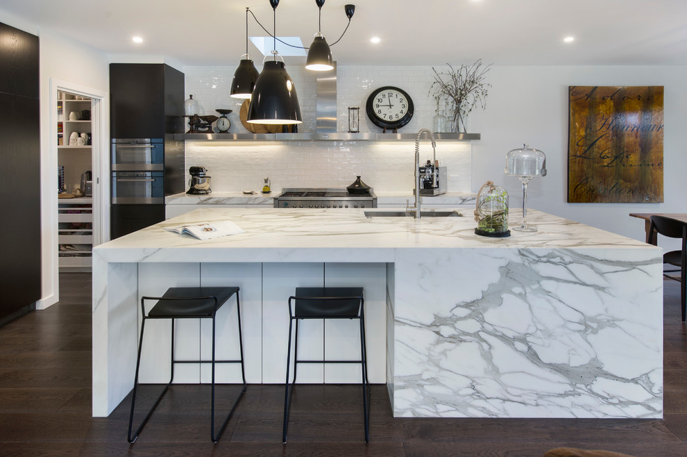 Inspiration for a mid-sized victorian l-shaped open plan kitchen in Melbourne with an undermount sink, dark wood cabinets, marble benchtops, white splashback, ceramic splashback, stainless steel appliances, medium hardwood floors and with island.