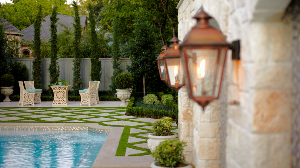 Design ideas for a mid-sized traditional backyard custom-shaped pool in Dallas with a water feature and natural stone pavers.