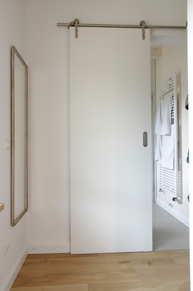 Inspiration for a small modern hallway in Other with white walls, light hardwood floors and beige floor.