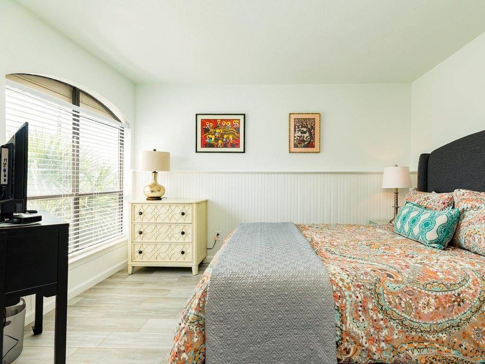 Mid-sized beach style bedroom in Houston with white walls, porcelain floors, no fireplace and beige floor.