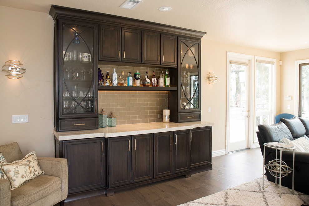 Photo of a mid-sized transitional l-shaped home bar in San Diego with an undermount sink, recessed-panel cabinets, dark wood cabinets, quartzite benchtops, glass tile splashback, medium hardwood floors, brown floor and white benchtop.