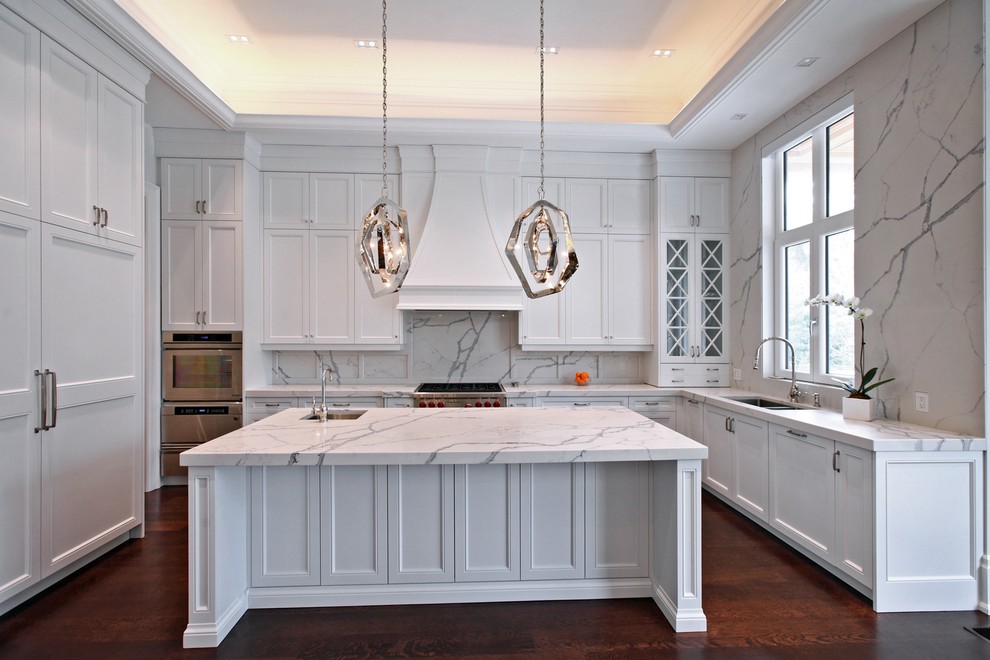 Large transitional u-shaped dark wood floor and brown floor open concept kitchen photo in Toronto with a double-bowl sink, shaker cabinets, white cabinets, marble countertops, white backsplash, stone slab backsplash, stainless steel appliances and an island