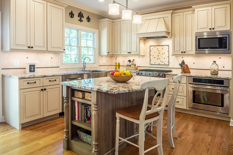 Example of a mid-sized transitional u-shaped light wood floor eat-in kitchen design in Chicago with a drop-in sink, recessed-panel cabinets, white cabinets, marble countertops, white backsplash, mosaic tile backsplash, stainless steel appliances and an island