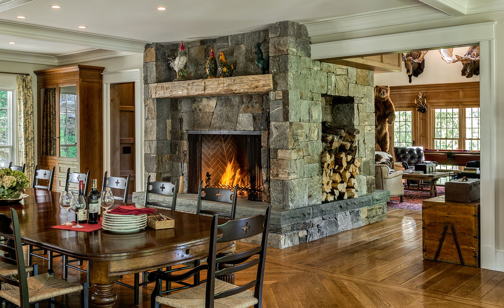 Mid-sized country kitchen/dining combo in New York with grey walls, medium hardwood floors, a standard fireplace and a stone fireplace surround.