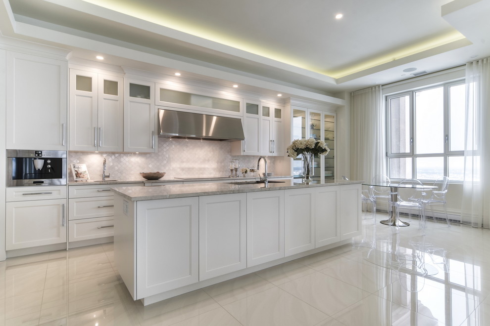 Mid-sized trendy u-shaped marble floor and white floor open concept kitchen photo in Montreal with an undermount sink, shaker cabinets, white cabinets, marble countertops, white backsplash, stone tile backsplash, stainless steel appliances and an island