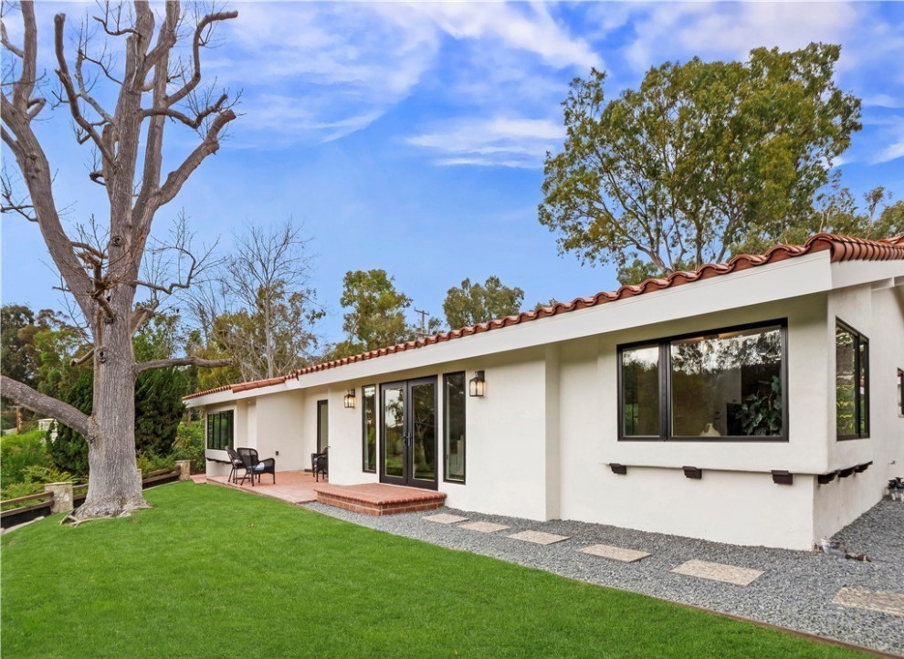 Large midcentury one-storey stucco white house exterior in Orange County with a gable roof, a tile roof and a red roof.