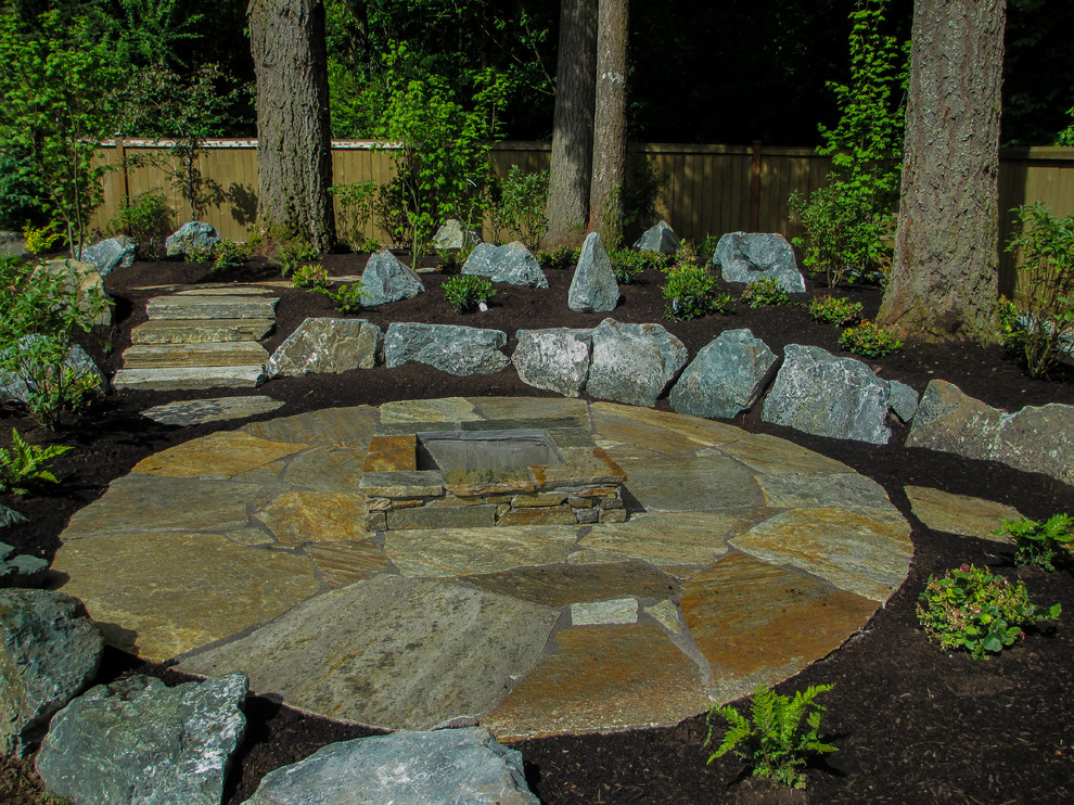 Design ideas for a mid-sized rustic partial sun backyard stone formal garden in Seattle with a fire pit for spring.
