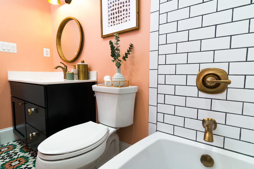 This is an example of a mid-sized contemporary 3/4 bathroom in DC Metro with recessed-panel cabinets, black cabinets, an alcove tub, a shower/bathtub combo, a two-piece toilet, white tile, subway tile, pink walls, an undermount sink, solid surface benchtops, multi-coloured floor, a shower curtain, white benchtops and ceramic floors.