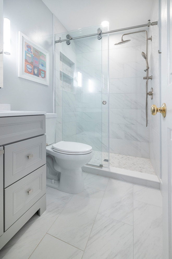 Bild på ett litet funkis vit vitt badrum för barn, med skåp i shakerstil, grå skåp, en dusch i en alkov, en toalettstol med hel cisternkåpa, vit kakel, porslinskakel, grå väggar, klinkergolv i porslin, ett integrerad handfat, bänkskiva i akrylsten, vitt golv och dusch med skjutdörr