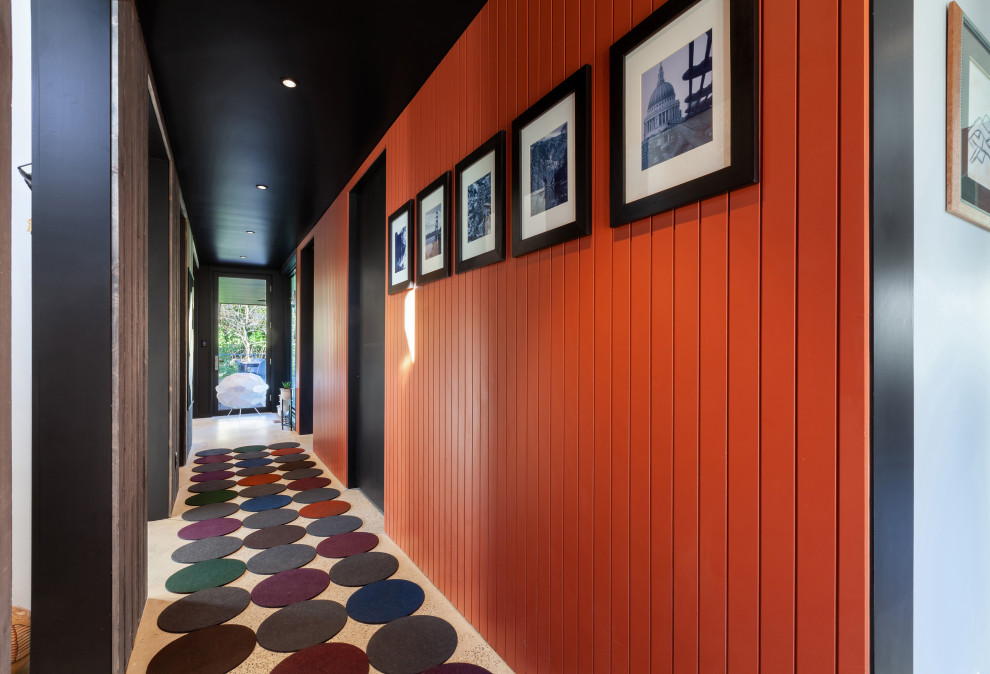 Idee per un piccolo ingresso o corridoio moderno con pareti arancioni, pavimento in cemento, pavimento grigio e pareti in legno
