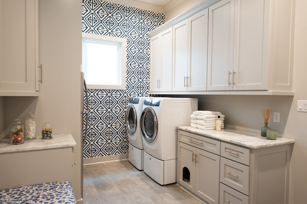 Design ideas for a transitional galley dedicated laundry room in Little Rock with shaker cabinets, grey cabinets, quartzite benchtops, grey walls, porcelain floors, a side-by-side washer and dryer, grey floor, white benchtop and wallpaper.