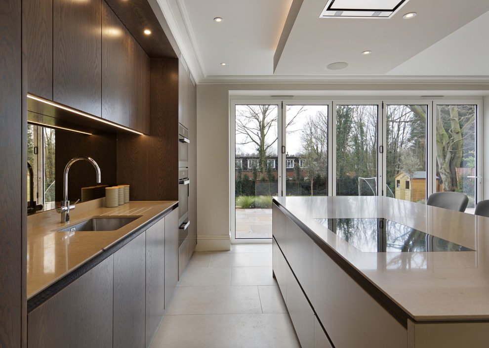 Large contemporary single-wall eat-in kitchen in Hertfordshire with an undermount sink, flat-panel cabinets, dark wood cabinets, quartzite benchtops, metallic splashback, mirror splashback, black appliances, porcelain floors, with island and white floor.