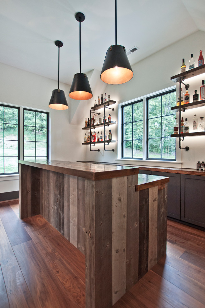 Mid-sized industrial l-shaped wet bar in Nashville with an undermount sink, shaker cabinets, grey cabinets, wood benchtops, medium hardwood floors, brown floor and brown benchtop.
