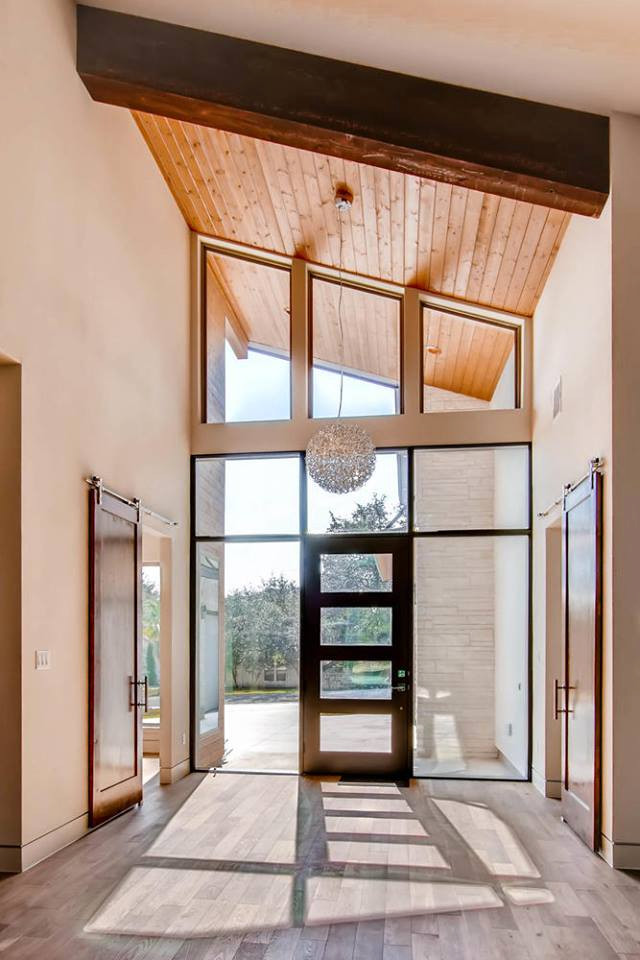 This is an example of a mid-sized contemporary foyer in Austin with white walls, ceramic floors, a single front door, a glass front door, grey floor and vaulted.