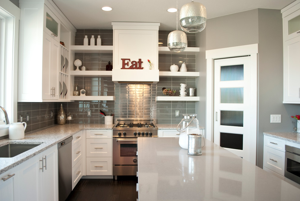 Transitional u-shaped kitchen photo with an undermount sink, recessed-panel cabinets, white cabinets, quartz countertops, gray backsplash, stainless steel appliances and an island
