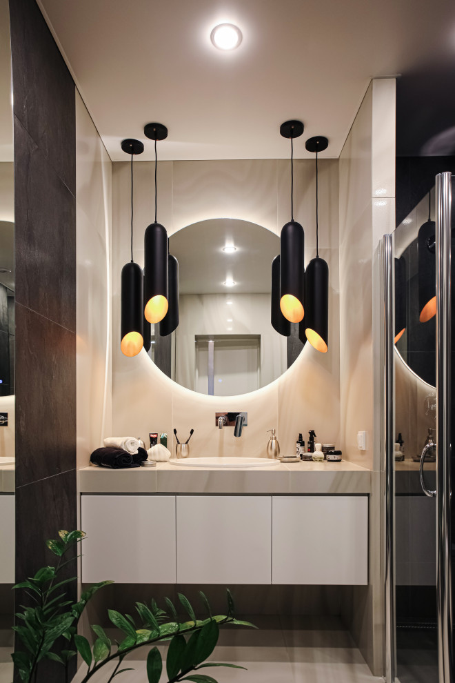 This is an example of a mid-sized contemporary 3/4 bathroom in Other with flat-panel cabinets, white cabinets, porcelain tile, porcelain floors, tile benchtops, a hinged shower door, beige tile, a drop-in sink, beige floor, beige benchtops and an alcove shower.