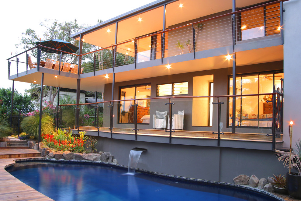 This is an example of a contemporary custom-shaped pool in Brisbane with decking and a water feature.
