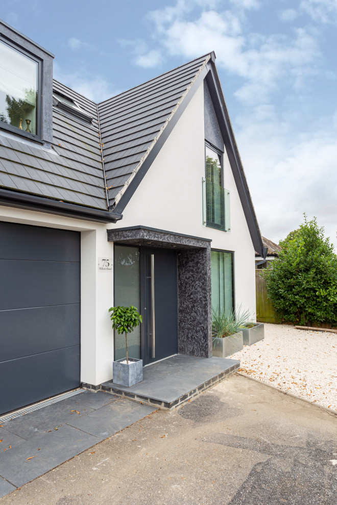 This is an example of a white contemporary two floor detached house in Oxfordshire with a pitched roof, a tiled roof and a grey roof.