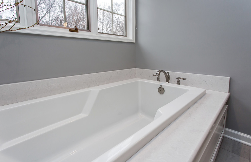 Inspiration for a mid-sized transitional master bathroom in Other with recessed-panel cabinets, white cabinets, a drop-in tub, an open shower, a two-piece toilet, grey walls, ceramic floors, an undermount sink, engineered quartz benchtops, grey floor, an open shower and white benchtops.