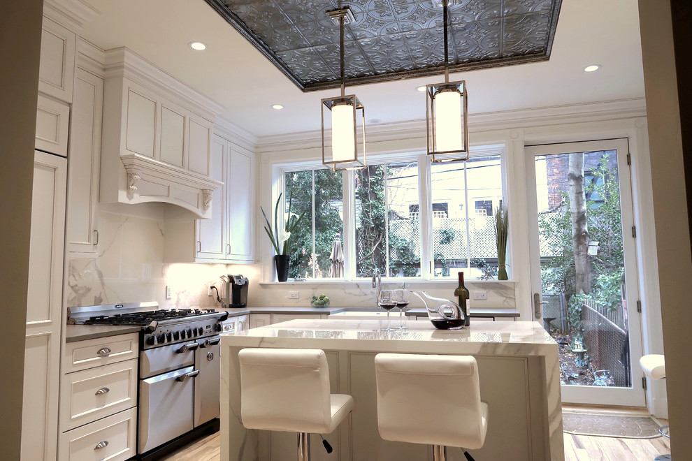 Small transitional u-shaped light wood floor and brown floor enclosed kitchen photo with a farmhouse sink, recessed-panel cabinets, white cabinets, quartz countertops, white backsplash, stone slab backsplash, stainless steel appliances, an island and white countertops
