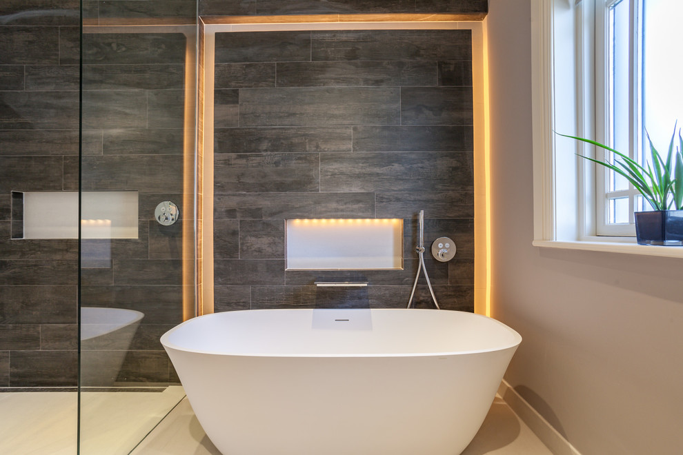 Inspiration for a contemporary bathroom in Dublin with a freestanding tub, brown tile and white floor.