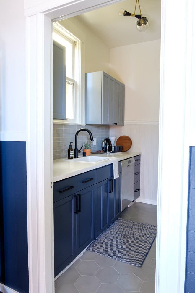 This is an example of a small contemporary single-wall eat-in kitchen in San Francisco with an undermount sink, shaker cabinets, blue cabinets, quartz benchtops, grey splashback, ceramic splashback, stainless steel appliances, ceramic floors, no island, grey floor and white benchtop.