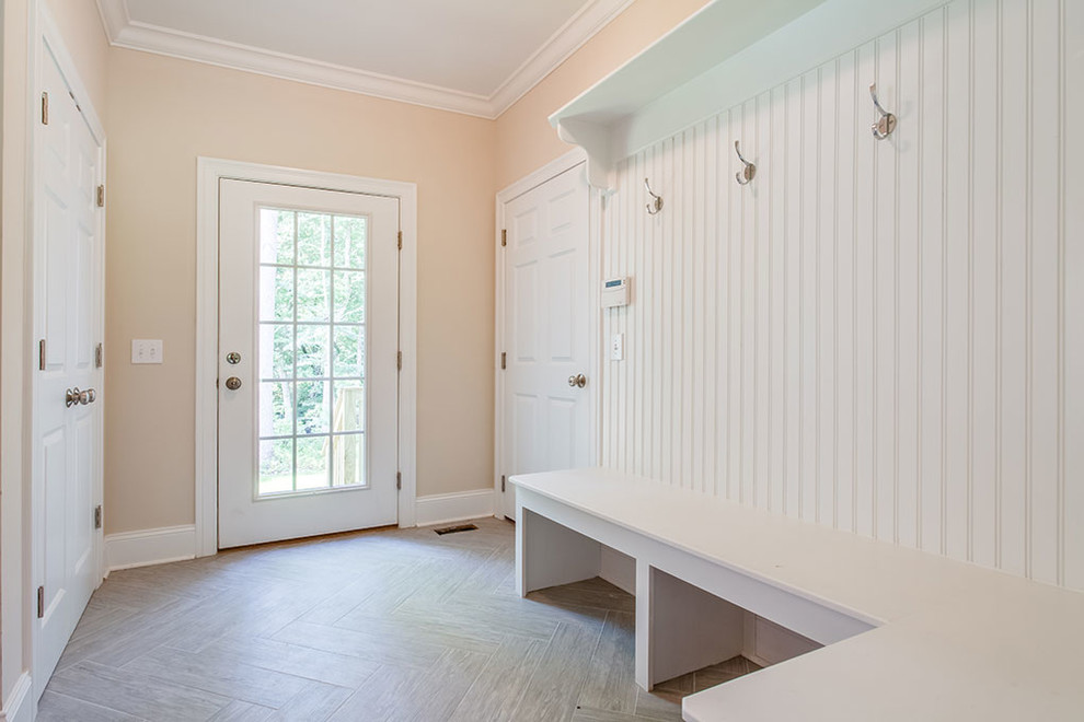 Example of a large transitional mudroom design with beige walls and a glass front door