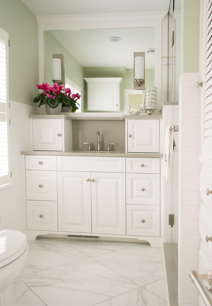 This is an example of a traditional master bathroom in Cedar Rapids with raised-panel cabinets, white cabinets, white tile, green walls, porcelain floors, a one-piece toilet and a single vanity.