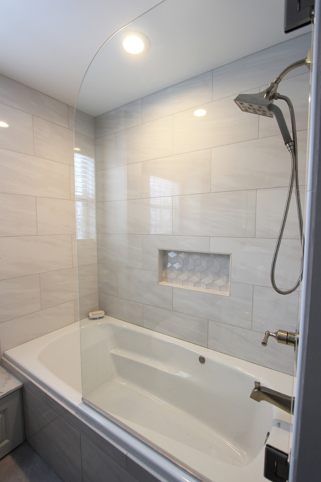 Inspiration for a small transitional master bathroom in Cleveland with raised-panel cabinets, grey cabinets, an alcove tub, an alcove shower, a two-piece toilet, gray tile, porcelain tile, grey walls, porcelain floors, an undermount sink, solid surface benchtops, grey floor and a hinged shower door.