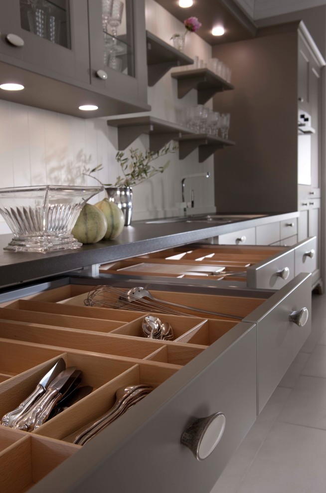 This is an example of a large traditional galley eat-in kitchen in New York with a double-bowl sink, shaker cabinets, grey cabinets, stainless steel appliances and light hardwood floors.