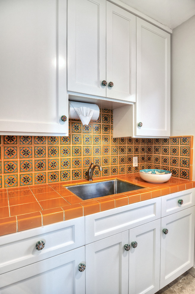 Mediterranean kitchen in Orange County with an undermount sink, tile benchtops, orange splashback, ceramic splashback, stainless steel appliances and orange benchtop.