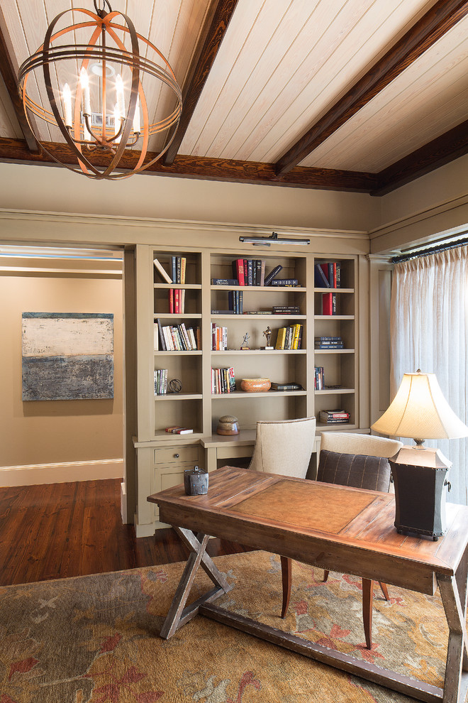 This is an example of a mid-sized traditional home office in Charleston with beige walls, dark hardwood floors and a freestanding desk.