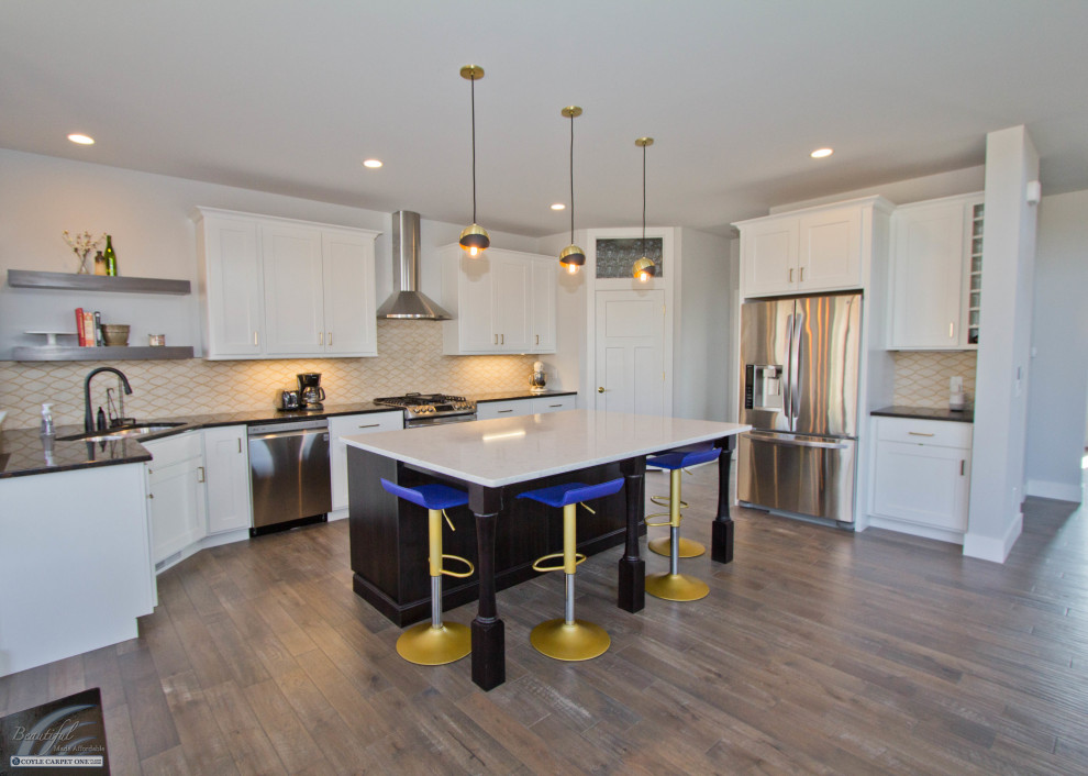 Example of a large transitional l-shaped medium tone wood floor and brown floor eat-in kitchen design with an undermount sink, recessed-panel cabinets, white cabinets, granite countertops, yellow backsplash, stainless steel appliances, an island and black countertops