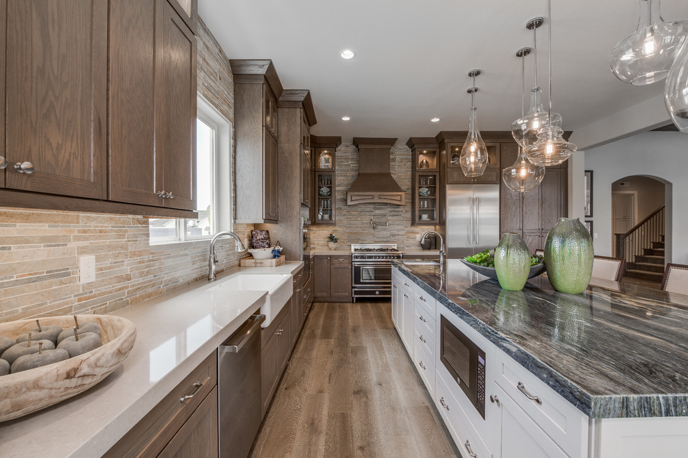 Large traditional eat-in kitchen in Salt Lake City with an undermount sink, recessed-panel cabinets, dark wood cabinets, granite benchtops, grey splashback, ceramic splashback, stainless steel appliances, light hardwood floors, with island and brown floor.