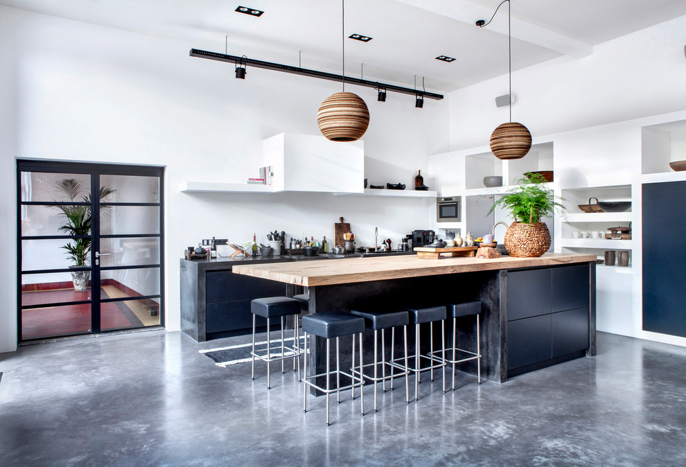 Design ideas for an industrial kitchen in Amsterdam with flat-panel cabinets, blue cabinets, white splashback, stainless steel appliances, concrete floors, with island and grey floor.