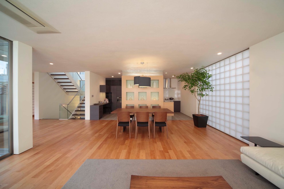 Asian open plan dining in Tokyo with white walls, medium hardwood floors and brown floor.