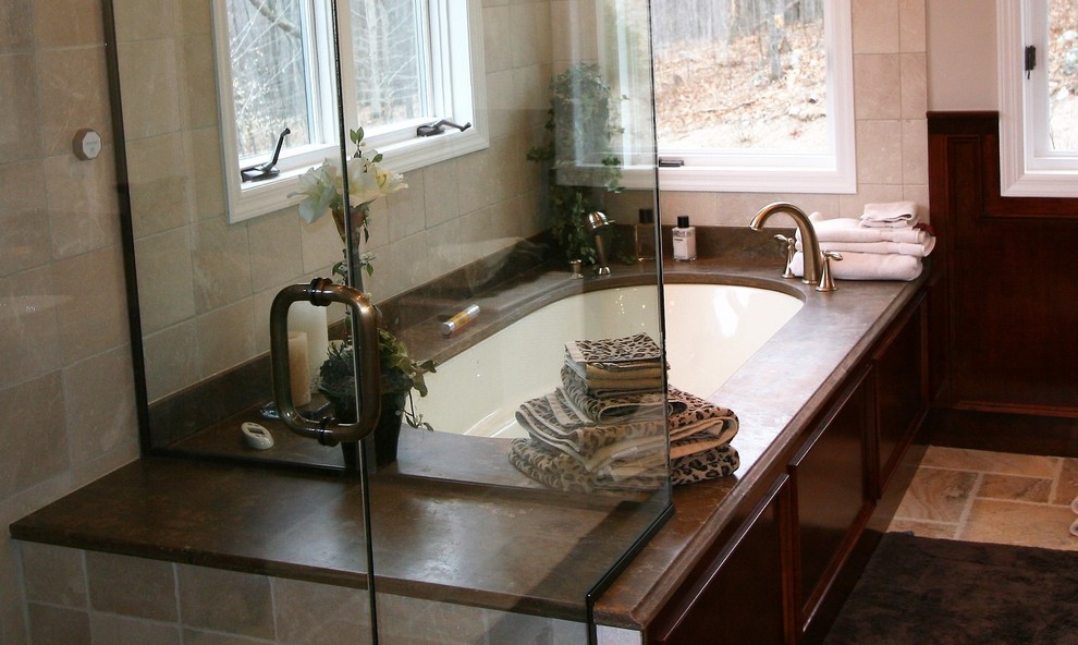 Design ideas for a large traditional master bathroom in New York with raised-panel cabinets, dark wood cabinets, a corner shower, beige tile, stone tile, granite benchtops, beige walls, ceramic floors, an undermount tub, brown floor, a hinged shower door, a two-piece toilet and an undermount sink.
