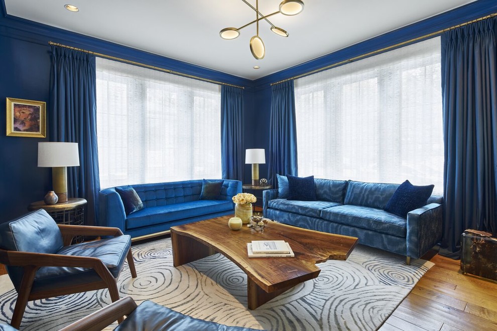 Large transitional formal enclosed living room in New York with blue walls, medium hardwood floors, a concealed tv and brown floor.
