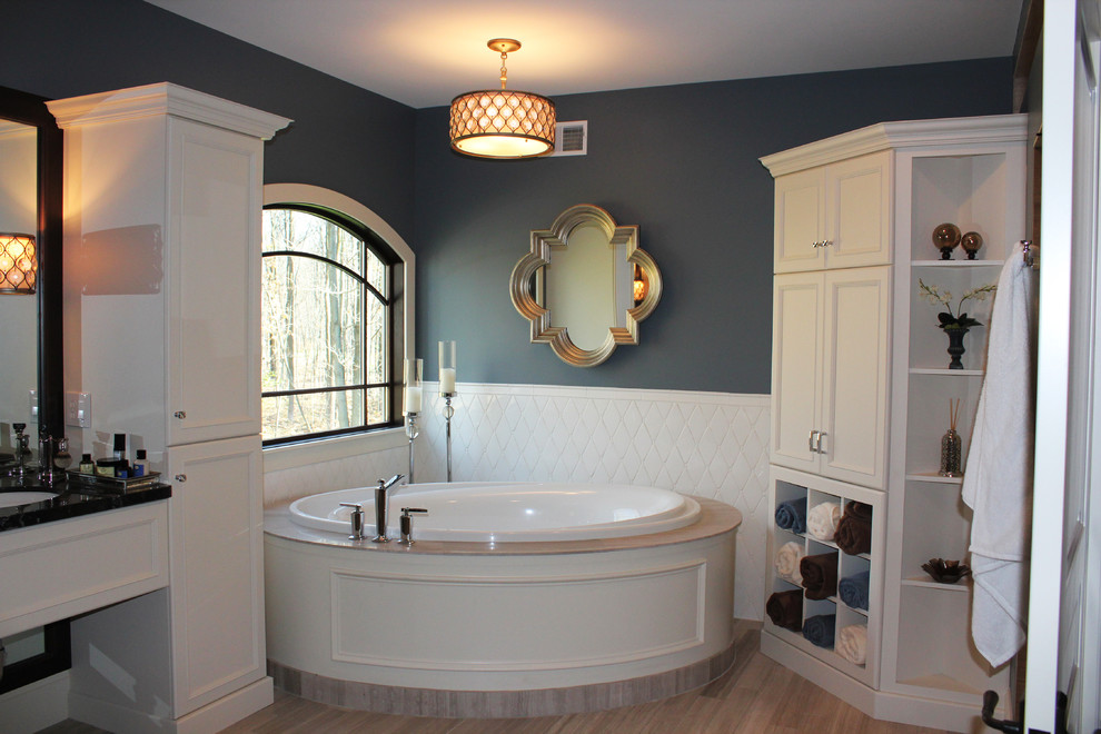Large transitional master bathroom in Other with recessed-panel cabinets, white cabinets, a corner tub, stone slab, blue walls, an undermount sink, solid surface benchtops and bamboo floors.