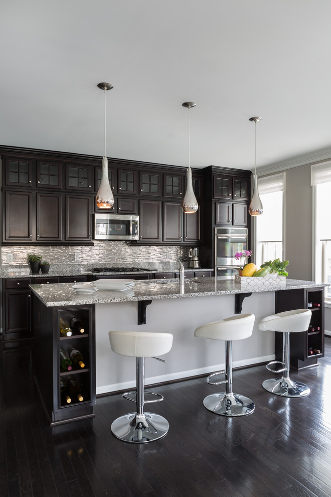 This is an example of a large transitional eat-in kitchen in DC Metro with raised-panel cabinets, dark wood cabinets, metallic splashback, stainless steel appliances, dark hardwood floors, with island, an undermount sink, granite benchtops and matchstick tile splashback.
