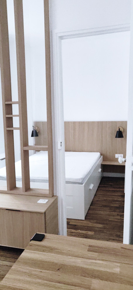 Idée de décoration pour une petite chambre d'amis design avec un mur blanc, parquet clair et un sol marron.