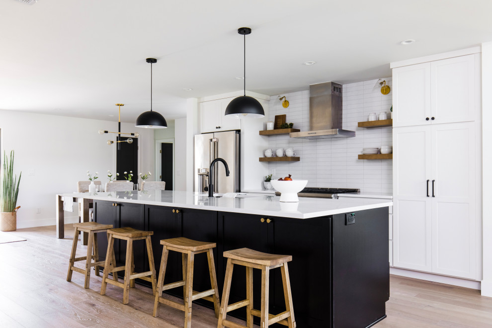 Example of a large transitional galley open concept kitchen design in Phoenix with a single-bowl sink, shaker cabinets, white cabinets, quartz countertops, white backsplash, ceramic backsplash, stainless steel appliances, an island and white countertops