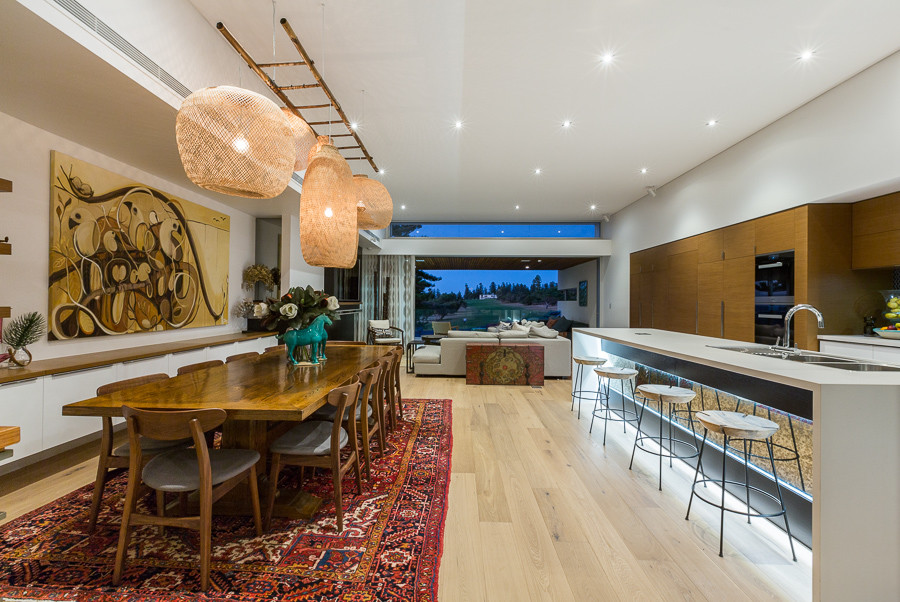 Photo of a large eclectic open plan dining in Perth with white walls, light hardwood floors, a ribbon fireplace and a stone fireplace surround.