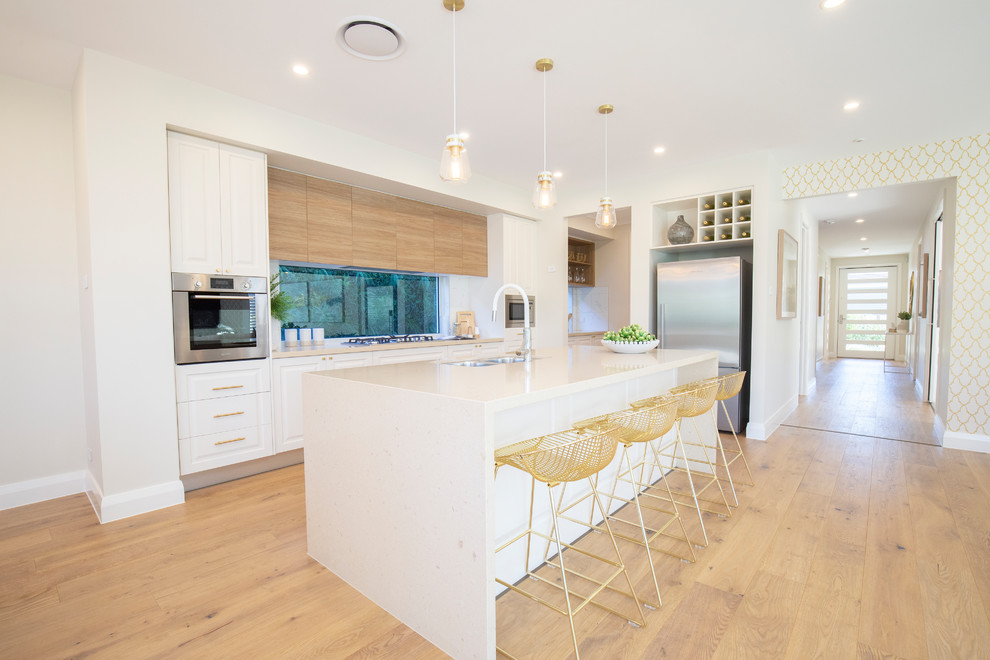 Inspiration for a contemporary eat-in kitchen in Central Coast with an undermount sink, raised-panel cabinets, white cabinets, window splashback, stainless steel appliances, light hardwood floors, with island, beige floor and white benchtop.