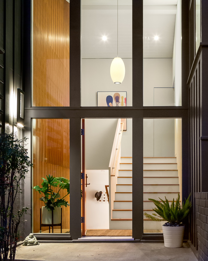 This is an example of a large midcentury foyer in San Francisco with white walls, a single front door, an orange front door and light hardwood floors.