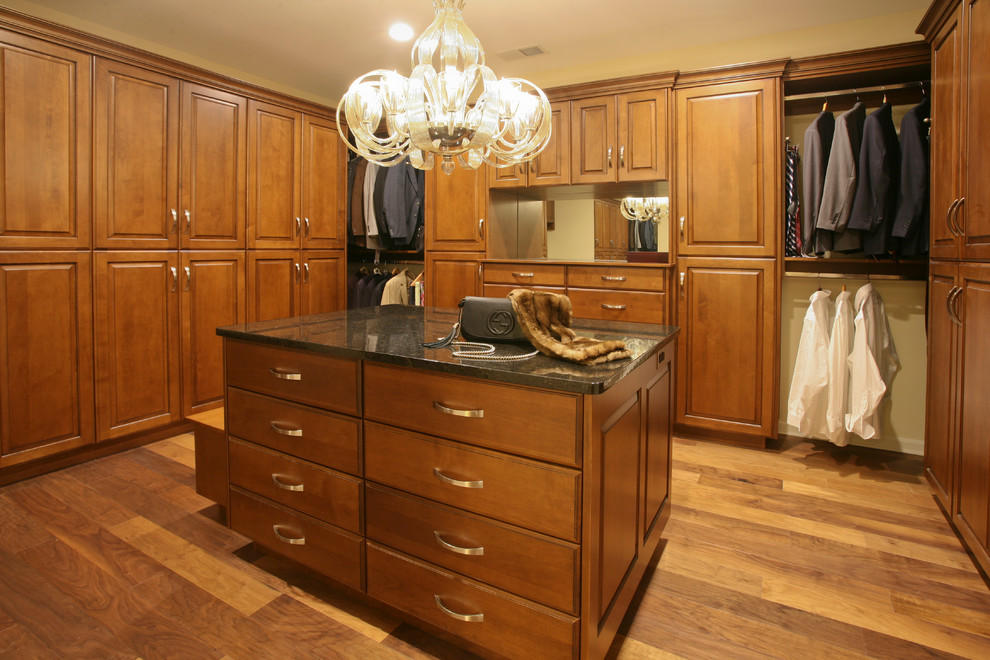 Photo of a large eclectic gender-neutral walk-in wardrobe in Other with medium hardwood floors, raised-panel cabinets, medium wood cabinets and brown floor.