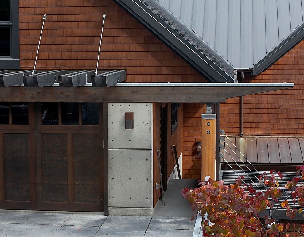 Large transitional three-storey brown house exterior in Seattle with wood siding, a gable roof and a metal roof.